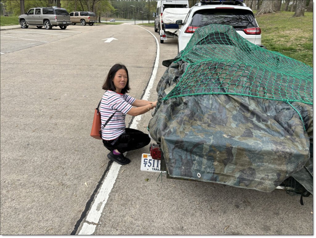 woman checking the covering of a utility trailer loaded with cargo