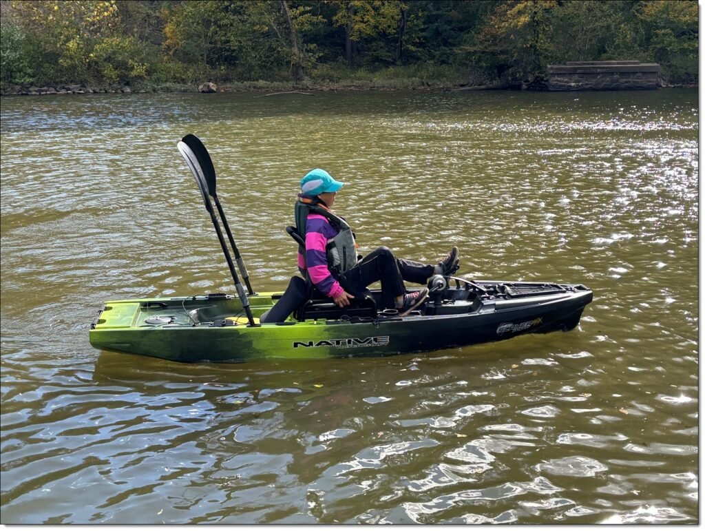 Winnie pedaling a native watercraft Slay Max Propel 10, with kayak paddle in the fishing rod holders 