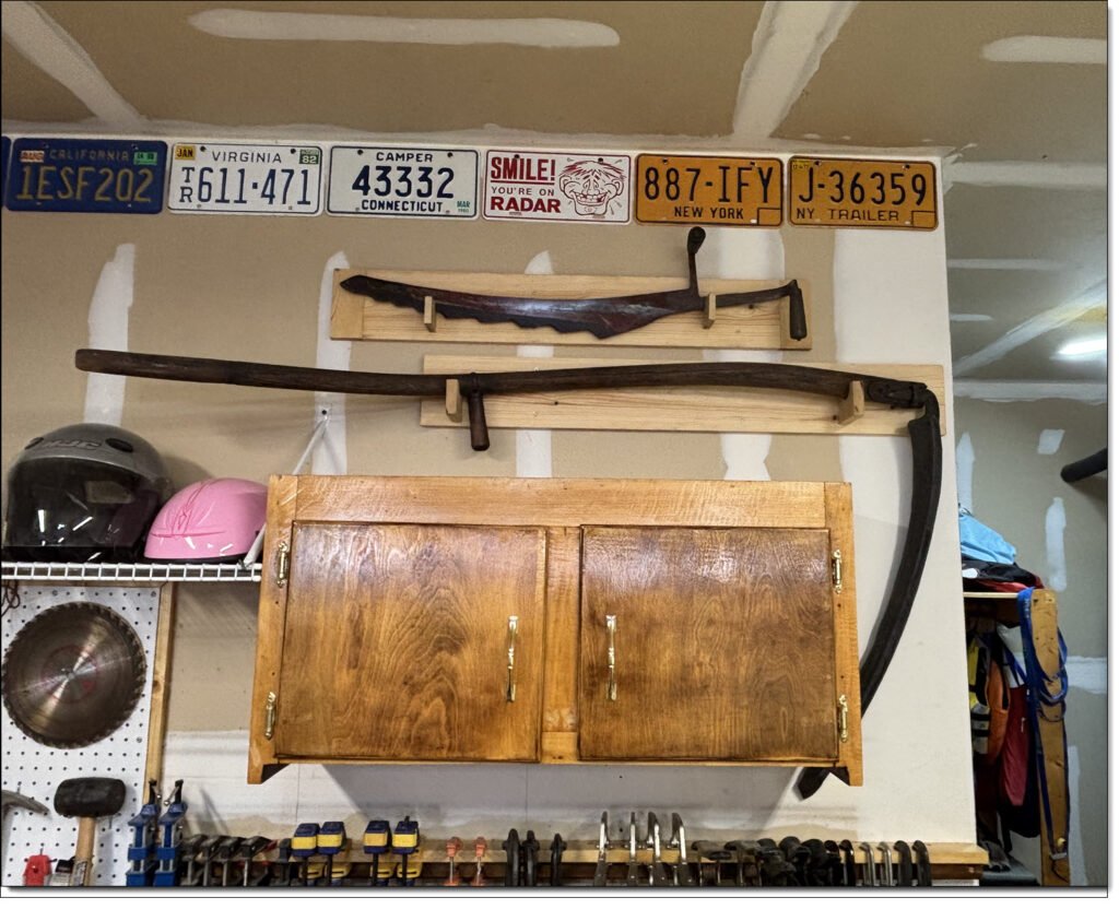 Early Americana License Plates wall-mounted Above a Vintage Ice Saw and Sickle