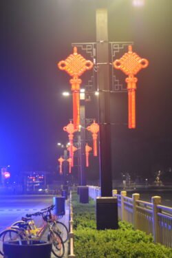Nighttime Street Scene in Xi'an night time street scene with red chinese knot lanterns illuminated as street lights. Several yellow bicycles are parked under the lights.