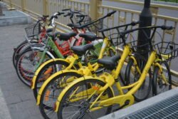 A Bevy of Rental Bikes in Xi'an a group of colorful heavy-framed bicycles locked in a bicycle rack on a sidewalk.