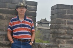 Ron Guarding a Battlement on the Old Xi'an City Wall Ron Charest posing next to a battlement of a stone wall, with a chinese guardhouse seen through the battlement
