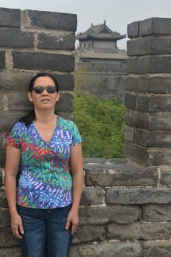 Winnie Guarding a Battlement on the Old Xi'an City Wall Winnie Charest posing next to a battlement of a stone wall, with a chinese guardhouse seen through the battlement