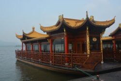 A Dragon Boat on West Lake An ornate floating barge with red wooden railings and posts supporting a yellow tiled roof in traditional chinese style