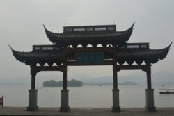 A Boat Landing on West Lake a large chinese-style gateway on a concrete pad at the edge of a lake.