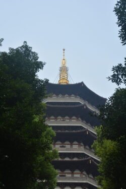 Leifeng Pagoda on West Lake in Hangzhou A Chinese pagoda topped with a golden spike, flanked by trees.