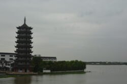 large pagoda on the edge of a waterway with plants at it's base.
