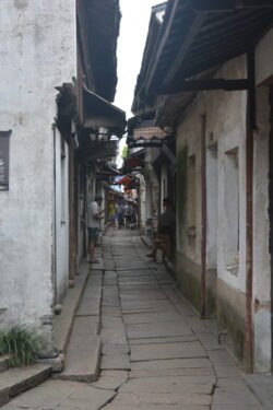 a narrow alley between whitewashed stone buildings with a pavestone walkway