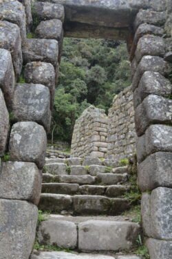 Looking through a stone doorway at stairs leading up the mountain to other former houses in the former farming village of  Wiñay Wayna .