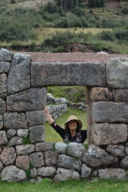 Woman with straw hat looking through a window in a stone wall