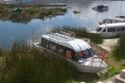 A typical commercial boat used for passengers and small cargo, nestled on the shore of Lake Titicaca, at the port of Puerto Luis Banchero Rossi