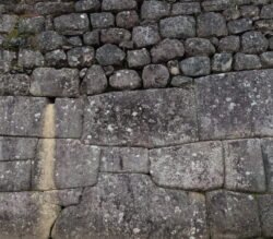 A stone retaining wall with Ashlar polygonal masonry construction in the lower section and sedimentary coursed masonry construction in the upper section. This wall includes a drain hole to prevent water pressure from building up behind it.