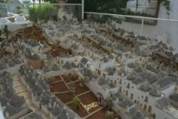 looking down on a scale model of a village composed of whitewashed stone houses with cone-shaped roofs.
