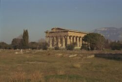 a view of a greek-style temple standing alone in an open field.