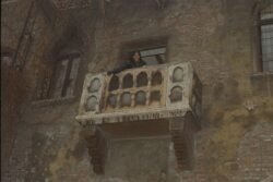 an ornate stone balcony with doorway in the stone wall behind it.