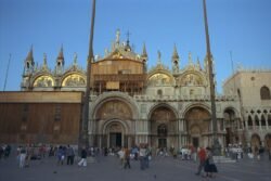 A ornate facade of a basilica, with gold decorations and topped with multiple onion-dome minarets
