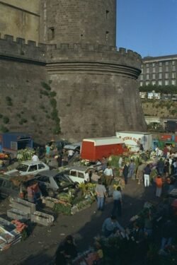 heavy castle stone walls with a rounded corner, and a marketplace on the street level