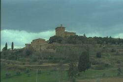 A fortified stone villa overlooking a scrub-covered hillside.