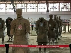 a group of terracotta warriors in a staging area in different levels of repair
