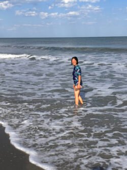 Weifang Charest standing knee-deep in the water of an ocean beach