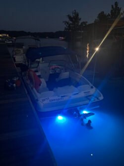 Looking at the stern of Bayliner 175BR boat at night with underwater lights activated.