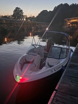 Looking at the bow of a Bayliner 175BR boat, sitting next to a pier, with nighttime running lights on