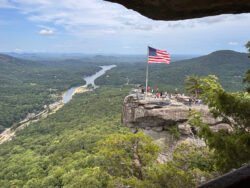 American flag flying over Chimney Rock, a natural stone formation located in North Carolina.
