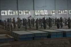 a group of terracotta warriors in a staging area in different levels of repair