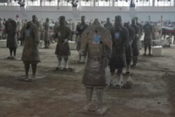 a group of terracotta warriors in a staging area in different levels of repair
