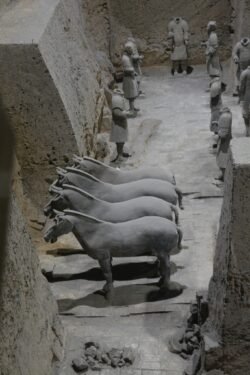 an open excavation trench with a group of horse figures and group of standing warriors