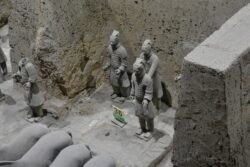 an open excavation trench with a group of horse figures and group of standing warriors