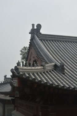 Details of a Temple Roof A classic Chinese hip-and-gable roof with flying eaves (upturned corners) and pronounced ridge tiles. Along the roof ridge are decorative figures, known as roof charms or figures