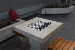 A Chessboard in a Park made of concrete, with chess pieces setup waiting for players