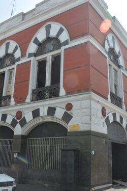 An ornate stone red and white building with tall arched windows with black and white arch stones.