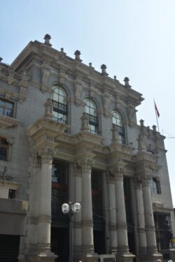 A building featuring prominent neoclassical architectural elements including Large columns with ornate capitals on the ground floor,  and arched windows with small balconies on the upper level