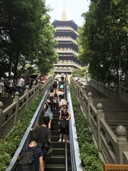 The Leifeng Pagoda in Hangzhou a outdoor escalator leading up to a chinese pagoda, with the escalator lined with carved stone railings