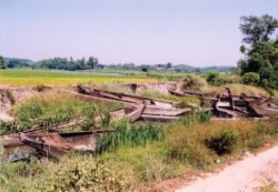 A stack of ferroconcrete canoes abandoned in a rice field. Outside of Leuchan, China, October 2003. For a period of time, the Chinese government experimented with building ferroconcrete canoes as an alternative to wood. This was not a successful project and eventually abandoned