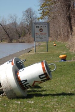 a white channel marker buoy laying on green grass next to the bank of the Erie Canal