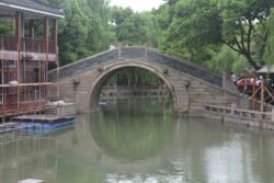 A Large Canal Bridge in Zhouzhuang a large stone arch bridge across a wide canal with trees behind it.