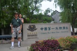 ron and winnie charest standing next to the famous stone marker at the entrance to Zhouzhuang, stating the town is the number one watertown and national tourist attraction as listed by the AAAAA