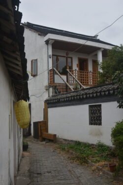 a straight walkway of pavestones winding through an alley with small buildings on each side.