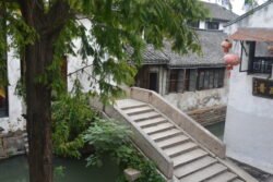 looking down at a stone arch bridge to see the staircase steps aiding pedestrian walkers.