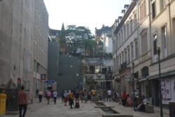 pedestrian zone featuring a large-scale 3D mural accessible by climbing the stairs in the background. An ALDI supermarket is visible on the left side of the street.