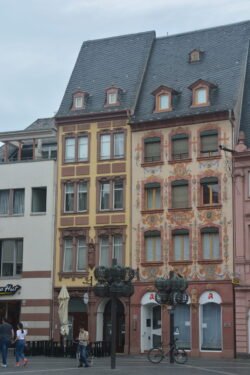 street scene of tall narrow townhouse-style buildings with decorative facades.