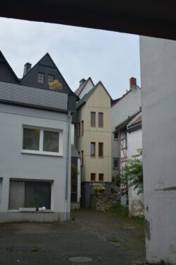 a very narrow townhouse tucked between to other buildings inside a courtyard.