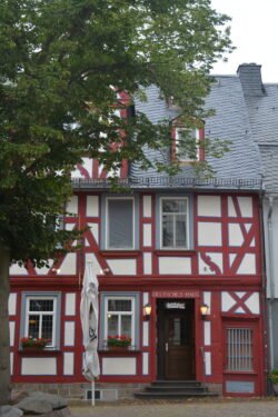 facing a half-timbered house of whitewashed stucco with red-painted wooden timbers