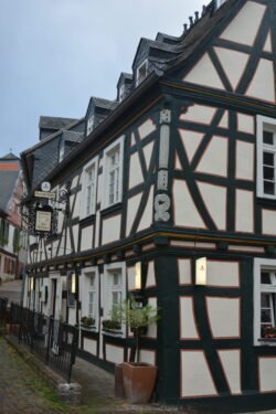 a corner view of a large half-timbered house of whitewashed stucco with dark wooden timbers