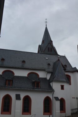 white stone church with conical steeple and dark roof