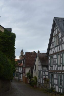 looking down a wide cobblestone street with half-timbered houses along the right side