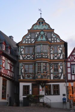 a highly decorated half-timbered house with elaborately detailed timber framing and a two-story bay window